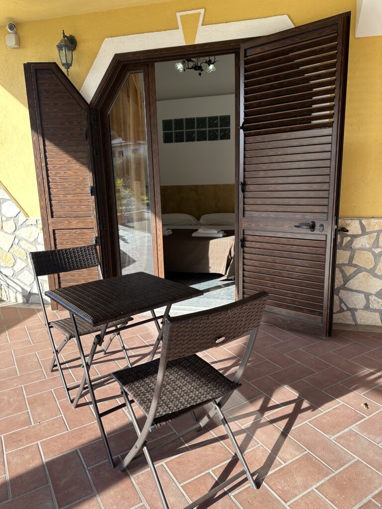 Tavolino e sedie sul patio, tra il verde della struttura